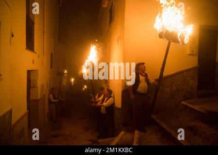 Malaga, Spanien, 12/12/2022, Dorfbewohner werden gesehen, wie sie Fackeln auf der Straße halten, während sie an der Feier der Jungfrauenprozession „Divina Pastora“ teilnehmen. Am Vorabend des Festes von St. Lucia im kleinen Dorf Casarabonela nehmen jeden Abend am 12. Dezember während der Weihnachtszeit an der antiken Feier der „Los rondeles“ Teil und tragen brennende Korbkörbe (auch bekannt als „Rondeles“) in Öl getränkt. Entlang der Straßen wird die Jungfrau von „Los rondeles“ von den Gläubigen in einem Ritual aus Licht und Feuer als Dankeschön für die Ernte geehrt. Stockfoto