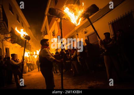 Malaga, Spanien, 12/12/2022, Dorfbewohner werden gesehen, wie sie Fackeln auf der Straße halten, während sie an der Feier der Jungfrauenprozession „Divina Pastora“ teilnehmen. Am Vorabend des Festes von St. Lucia im kleinen Dorf Casarabonela nehmen jeden Abend am 12. Dezember während der Weihnachtszeit an der antiken Feier der „Los rondeles“ Teil und tragen brennende Korbkörbe (auch bekannt als „Rondeles“) in Öl getränkt. Entlang der Straßen wird die Jungfrau von „Los rondeles“ von den Gläubigen in einem Ritual aus Licht und Feuer als Dankeschön für die Ernte geehrt. Stockfoto