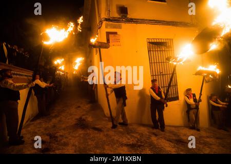 Malaga, Spanien, 12/12/2022, Dorfbewohner werden gesehen, wie sie Fackeln auf der Straße halten, während sie an der Feier der Jungfrauenprozession „Divina Pastora“ teilnehmen. Am Vorabend des Festes von St. Lucia im kleinen Dorf Casarabonela nehmen jeden Abend am 12. Dezember während der Weihnachtszeit an der antiken Feier der „Los rondeles“ Teil und tragen brennende Korbkörbe (auch bekannt als „Rondeles“) in Öl getränkt. Entlang der Straßen wird die Jungfrau von „Los rondeles“ von den Gläubigen in einem Ritual aus Licht und Feuer als Dankeschön für die Ernte geehrt. Stockfoto