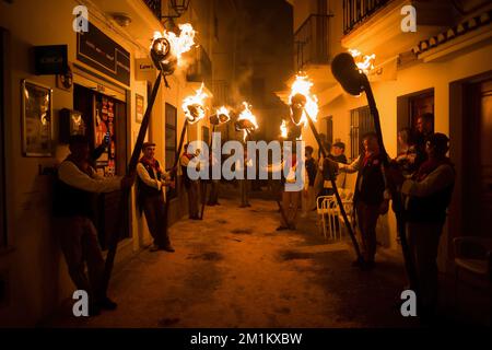 Malaga, Spanien, 12/12/2022, Dorfbewohner werden gesehen, wie sie Fackeln auf der Straße halten, während sie an der Feier der Jungfrauenprozession „Divina Pastora“ teilnehmen. Am Vorabend des Festes von St. Lucia im kleinen Dorf Casarabonela nehmen jeden Abend am 12. Dezember während der Weihnachtszeit an der antiken Feier der „Los rondeles“ Teil und tragen brennende Korbkörbe (auch bekannt als „Rondeles“) in Öl getränkt. Entlang der Straßen wird die Jungfrau von „Los rondeles“ von den Gläubigen in einem Ritual aus Licht und Feuer als Dankeschön für die Ernte geehrt. Stockfoto