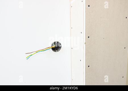 Freiliegende Steckdose mit entfernter oberer Abdeckung für die Installation der Verkabelung an der Putzwand des im Bau befindlichen Gebäudes. Stockfoto