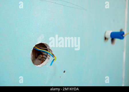 Freiliegende Steckdose mit entfernter oberer Abdeckung für die Installation der Verkabelung an der Putzwand des im Bau befindlichen Gebäudes. Stockfoto