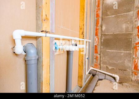 Neue Wasserinstallation, freiliegende graue PVC-Abwasserrohre an der Gipskartonwand montiert. Stockfoto