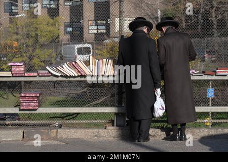 Zwei orthodoxe jüdische Männer, gekleidet in einem schwarzen Laden für religiöse Bücher, bei einem Buchverkauf in Brooklyn, New York City. Stockfoto