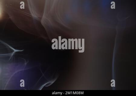 Anmutige Wirbel von Räucherrauch auf schwarzem Hintergrund. Vapor Nahaufnahme. Soft Focus, Struktur und Lichtreflexionen von Helios 44m-4 Vintage Objektiv. Abstrakter Hintergrund. Stockfoto