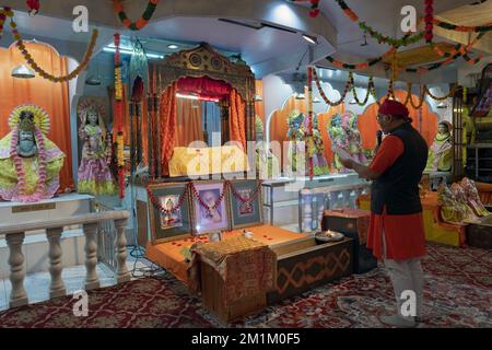 Ein hinduistischer Priester liest persönliche Nachrichten bei einem Gottesdienst im Satya Narayan Mandir in Woodside, Queens, New York. Stockfoto