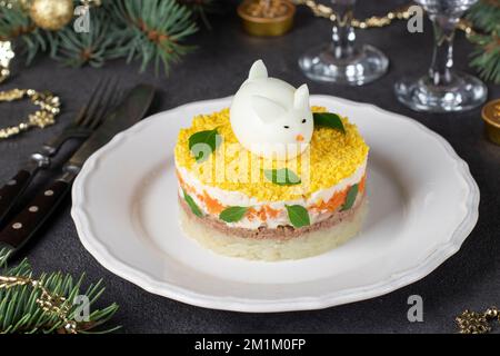 Festlicher Salat Mimosa zum Neujahr mit Thunfischkonserven, Kartoffeln und Karotten, dekoriertem Hasen aus Ei Stockfoto