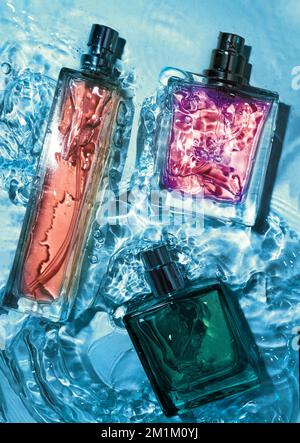 Ansicht von unten auf dem Set der Sprühflasche mit Parfüm steht auf einem Glastisch in blauer Farbe. Stockfoto