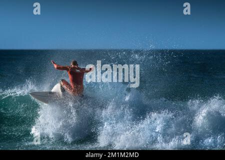 Spektakuläre Surfaktion als männlicher Surfer reitet auf einer Welle im Fistral in Newquay in Cornwall in England in Großbritannien. Stockfoto