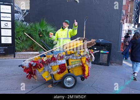 Staubmann Arbeiter Straßenreiniger mit Weihnachtsdekorationen auf seinem Staubwagen in Islington London England UK Dezember 2022 Großbritannien KATHY DEWITT Stockfoto