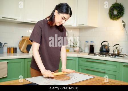 Junge, wunderschöne brünette Frau mit ihren 30s Köchen in der Küche Stockfoto