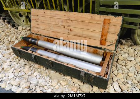 Schalen für den Tank in einer grünen Holzkiste auf den Felsen in der Nähe des Tanks. Lieferung von Militärmunition. Stockfoto