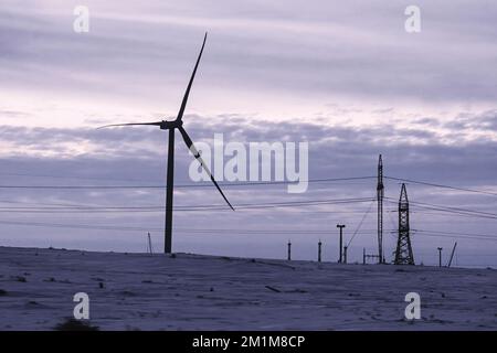 Windturbine auf verschneitem Feld bei Sonnenaufgang. Alternative grüne energieenergieenergie im Winter. Alternative Energiequellen. Umweltfreundliche Elektrizität Stockfoto