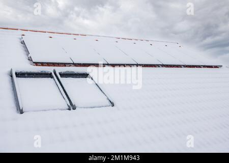 Die schneebedeckten Sonnenkollektoren auf dem Dach. Stockfoto