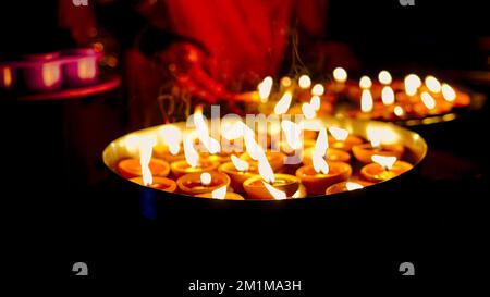 Viele Diya- oder traditionelle Tonlampen auf dem Diwali Festival. Eine Mädchenhand, die beim deepavali-Festival eine Öllampenplatte in der Hand hält. Indische Hindu-Religion Stockfoto