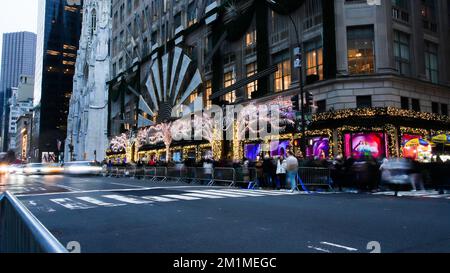 NEW YORK, NY, USA - 10. DEZEMBER 2022: Blick von der belebten 5. Avenue in der Nähe des Saks Stores, mit Lichtern dekoriert Stockfoto