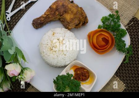 Hausgemachtes indonesisches Essen, Hähnchenbutter mit weißem Reis, Gemüse, Tomaten und Chilisauce Stockfoto