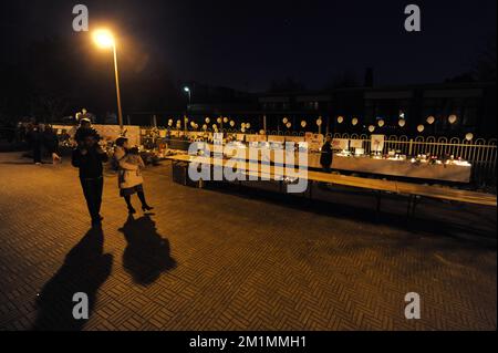 20120315 - LOMMEL, BELGIEN: Abbildung zeigt Menschen, die an den Gittern der Schule vorbeifahren, bedeckt mit Roten und Kerzen, während einer Gedenkfeier in Lommel, zu Ehren der Opfer des Busunfalls in der Schweiz, Donnerstag, den 15. März 2012. Bei einem schrecklichen Busunfall am Dienstagabend in einem Tunnel, in Sierre, Valais, Schweiz, 28 Menschen, Darunter 22 Kinder, starben, 24 andere wurden verletzt. Die Kinder aus zwei Schulen von Lommel und Heverlee waren nach dem Skiurlaub auf dem Heimweg. BELGA FOTO YORICK JANSENS Stockfoto