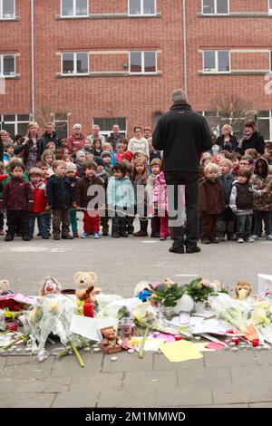 20120316 Uhr - HEVERLEE, BELGIEN: Kinder auf dem Spielplatz vor Blumen, Teddybären und Kerzen während der Schweigeminute am Tag der belgischen nationalen Trauer, rund um die Grundschule (Basisschool - ecole Primaire) Sint-Lambertusschool, in Heverlee, Freitag, 16. März 2012. Bei einem schrecklichen Busunfall am Dienstagabend in einem Tunnel, in Sierre, Valais, Schweiz, 28 Menschen, Darunter 22 Kinder, starben, 24 andere wurden verletzt. Die Kinder aus zwei Schulen von Lommel und Heverlee waren nach dem Skiurlaub auf dem Heimweg. BELGA FOTO CHRISTOPHE LEGASSE Stockfoto