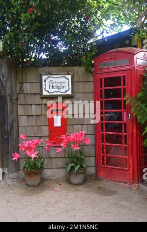 Rote britische Telefonzelle „Kiosk“ und rote Briefbox in einer Mauer am Eingang zu den Lost Gardens of Heligan, St. Austell, Cornwall, Großbritannien Stockfoto