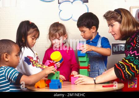 Schullehrer mit Kindern baut mit Bausteinen Stockfoto