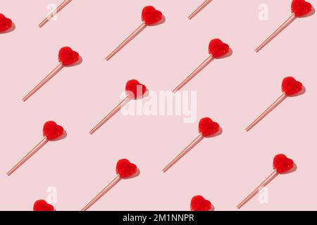 Rotes herzförmiges Lutschmuster auf pastellfarbenem Hintergrund. Minimales Valentinstag-oder-Liebe-Konzept. Stockfoto