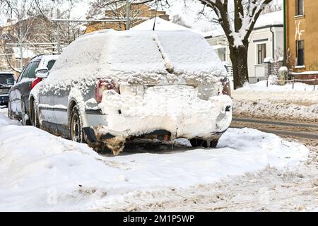 Riga, Lettland - 13. Dezember 2022: Gefrorenes Auto mit Schneeschicht am Wintertag auf der Straße der Stadt geparkt. Stockfoto