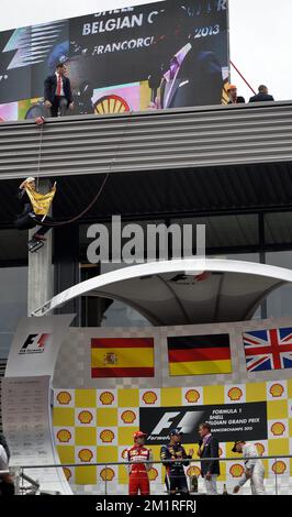 Abbildung zeigt eine Aktion von Greenpeace auf dem Podium des spanischen Fernando Alonso von Ferrari, des deutschen Sebastian Vettel von Red Bull Racing und des britischen Lewis Hamilton von Mercedes nach dem Großen Preis F1 von Belgien, in Spa-Francorchamps, Sonntag, 25. August 2013. Der Spa-Francorchamps Formel 1 Grand Prix findet an diesem Wochenende vom 23. August bis 25. August statt. BELGA FOTO ERIC LALMAND Stockfoto