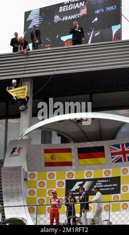 Abbildung zeigt eine Aktion von Greenpeace auf dem Podium des spanischen Fernando Alonso von Ferrari, des deutschen Sebastian Vettel von Red Bull Racing und des britischen Lewis Hamilton von Mercedes nach dem Großen Preis F1 von Belgien, in Spa-Francorchamps, Sonntag, 25. August 2013. Der Spa-Francorchamps Formel 1 Grand Prix findet an diesem Wochenende vom 23. August bis 25. August statt. BELGA FOTO ERIC LALMAND Stockfoto
