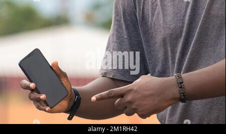 Hand eines jungen schwarzen afrikaners mit weißem Smartphone Stockfoto