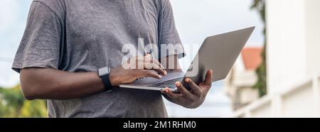 Schwarzafrikanische Hand hält und benutzt ein Mobiltelefon mit leerem Bildschirm horizontal Stockfoto