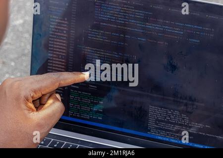 Handporträt eines afrikanischen Webentwicklers, der mit dem Finger auf eine Zeile Computercode zeigt Stockfoto