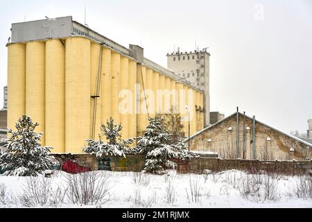 Riga, Lettland - 13. Dezember 2022: Ein altes großes gelbes Getreidelager in der Wintersaison Stockfoto