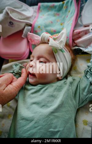 2 Wochen altes Baby, das beim Streicheln des Gesichts einen Wurzelreflex auspuckt. Stockfoto