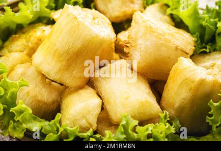 Gebratener Kassava, Snack aus Kassava-Wurzel und serviert mit Salat, traditionelle südamerikanische Restaurantgarnierung, brasilianisches Restaurant für Stockfoto