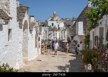 Weiß getünchte Trulli Häuser und Souvenirläden entlang der Straße in der Altstadt, Alberobello, Apulien, Italien, Europa Stockfoto