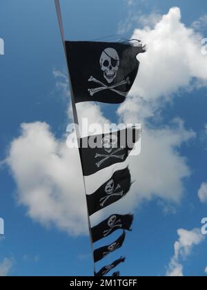 Schädel- und Crossbones-Piratenflaggen flattern in einer Penzance-Brise. Stockfoto