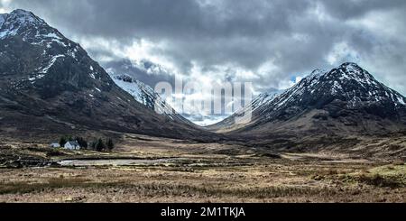 Sturmwolken über dem U-förmigen Tal und üppige Hütte auf Glencoe in den westlichen Highlands. Stockfoto