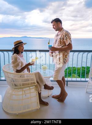 Ein paar Männer und Frauen trinken Cocktails auf dem Balkon eines Hotels in Pattaya Thailand bei Sonnenuntergang. Stockfoto