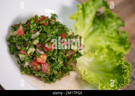 Gericht aus dem nahöstlichen Tabbouleh-Salat mit Salat auf weißem Hintergrund. Stockfoto