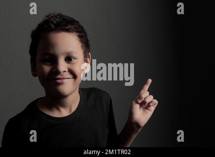 Das Kind zeigt auf weißem Hintergrund und greift nach oben zum Himmel mit einem Stockfoto Stockfoto