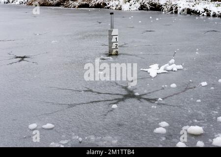 Zerbrochenes, dünnes Eis auf einem gefrorenen Teich. UK Stockfoto