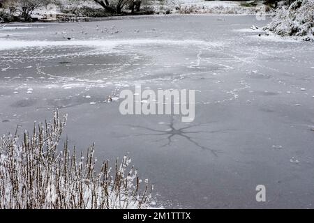 Zerbrochenes, dünnes Eis auf einem gefrorenen Teich. UK Stockfoto