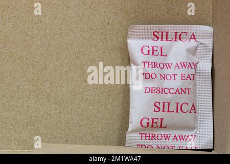 Eine Packung Kieselgel in der unteren Ecke einer Faltschachtel. Poröse Trockenmittelsubstanz, die im Verpackungsmaterial zur Aufnahme von Feuchtigkeit verwendet wird. Stockfoto