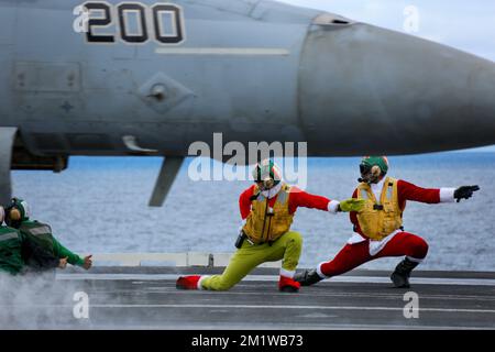 San Diego, Usa. 10.. Dezember 2022. USA Navy Deck Crew LT. Commander. Andrew Castro, Left, und LT. Brandon Russell ziehen Weihnachtskostüme an, während sie Flugzeugen den Start auf dem Cockpit des Flugzeugträgers USS Abraham Lincoln signalisieren, am 10. Dezember 2022 vor der Küste Kaliforniens. Kredit: MC3 Ian Thomas/Planetpix/Alamy Live News Kredit: Planetpix/Alamy Live News Stockfoto