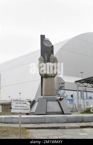 Denkmal der Tschernobyl-Liquidators in der Nähe der Reaktorkuppel von 4. im Hintergrund Stockfoto