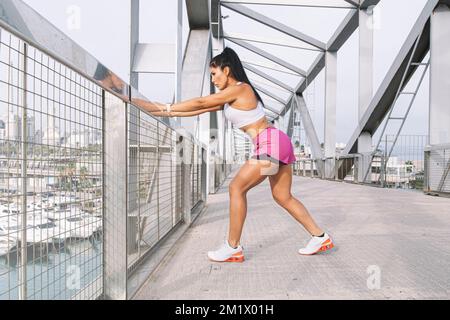 Attraktive Sportlerin mittleren Alters mit Beindehnung. Draußen in der Stadt trainieren Stockfoto