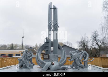 Ein Schönheitsdenkmal, das einem Feuerwehrmann gewidmet ist, der in der nuklearen Katastrophe von tschernobyl diente, mit Feuerwache und bewölktem Himmel im Hintergrund Stockfoto