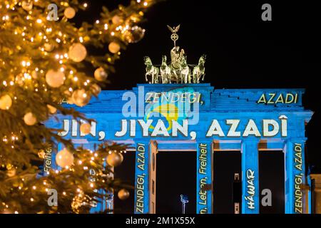 Berlin, Deutschland. 13.. Dezember 2022. Das Brandenburger Tor wird während eines Protests für Solidarität mit den Protesten im Iran mit der persischen Schrift "Zan - Zendegi - Azadi" ("Frau - Leben - Freiheit") beleuchtet. Kredit: Christoph Soeder/dpa/Alamy Live News Stockfoto