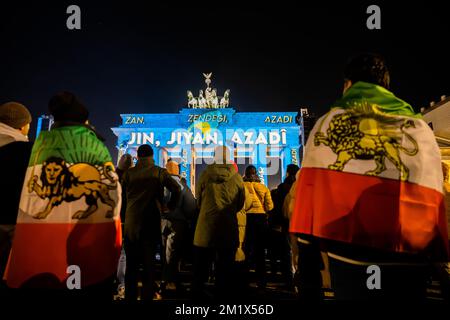 Berlin, Deutschland. 13.. Dezember 2022. Das Brandenburger Tor wird während eines Protests für Solidarität mit den Protesten im Iran mit der persischen Schrift "Zan - Zendegi - Azadi" ("Frau - Leben - Freiheit") beleuchtet. Kredit: Christoph Soeder/dpa/Alamy Live News Stockfoto